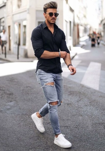 Man walking in black shirt, ripped jeans